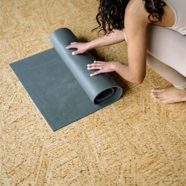 Rolled up turquoise yoga mat on wooden floor